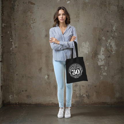Woman holding the Being 30 is a Work of Art 30th birthday tote bag in black