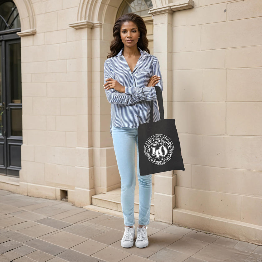 Woman holding the Being 40 is a Work of Art 40th birthday tote bag in black