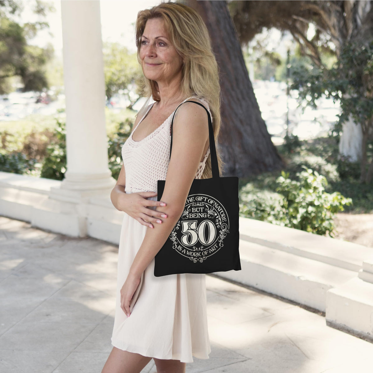 Woman carrying the black Being 50 is a Work of Art 50th birthday tote bag