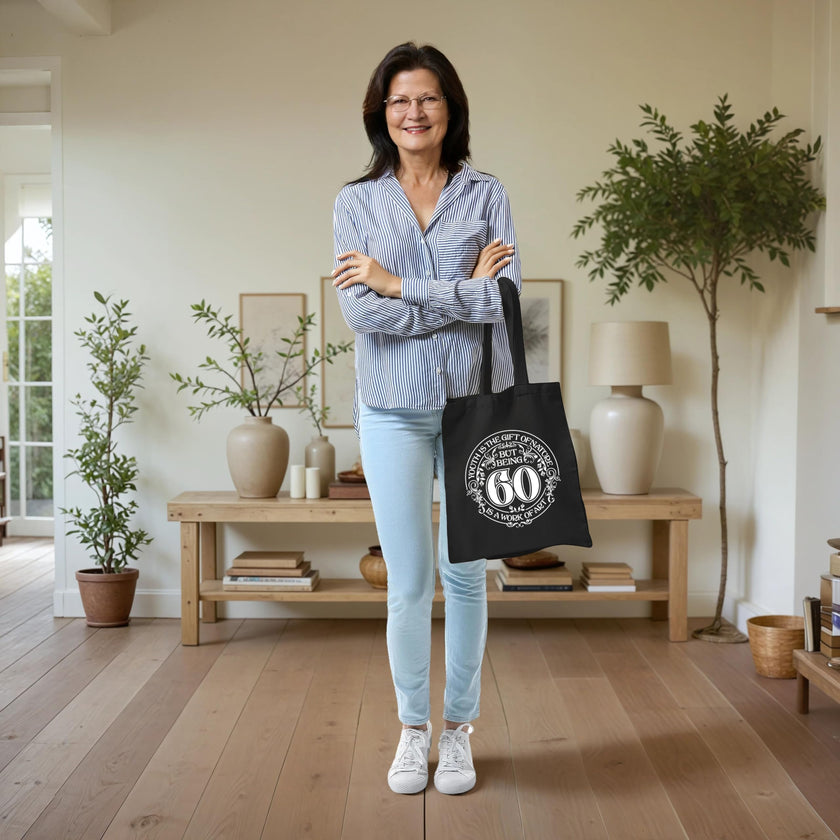 Woman holding the Being 60 is a Work of Art 60th birthday tote bag in black