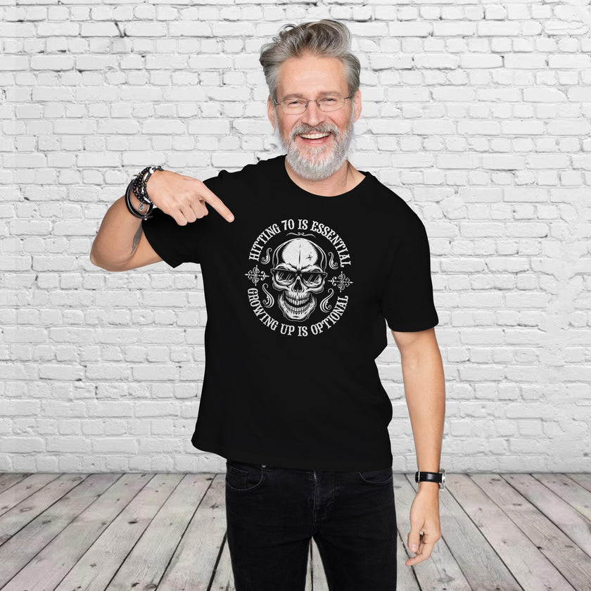 Man pointing at the Hitting 70 is Essential print on his black 70th birthday t-shirt