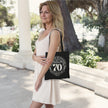 Woman carrying the black Being 70 is a Work of Art 70th birthday tote bag