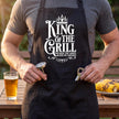 Close-up of the King of the Grill apron pocket holding a thermometer and bottle opener
