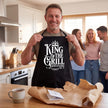 Man unwrapping a King of the Grill apron gift with family in the kitchen