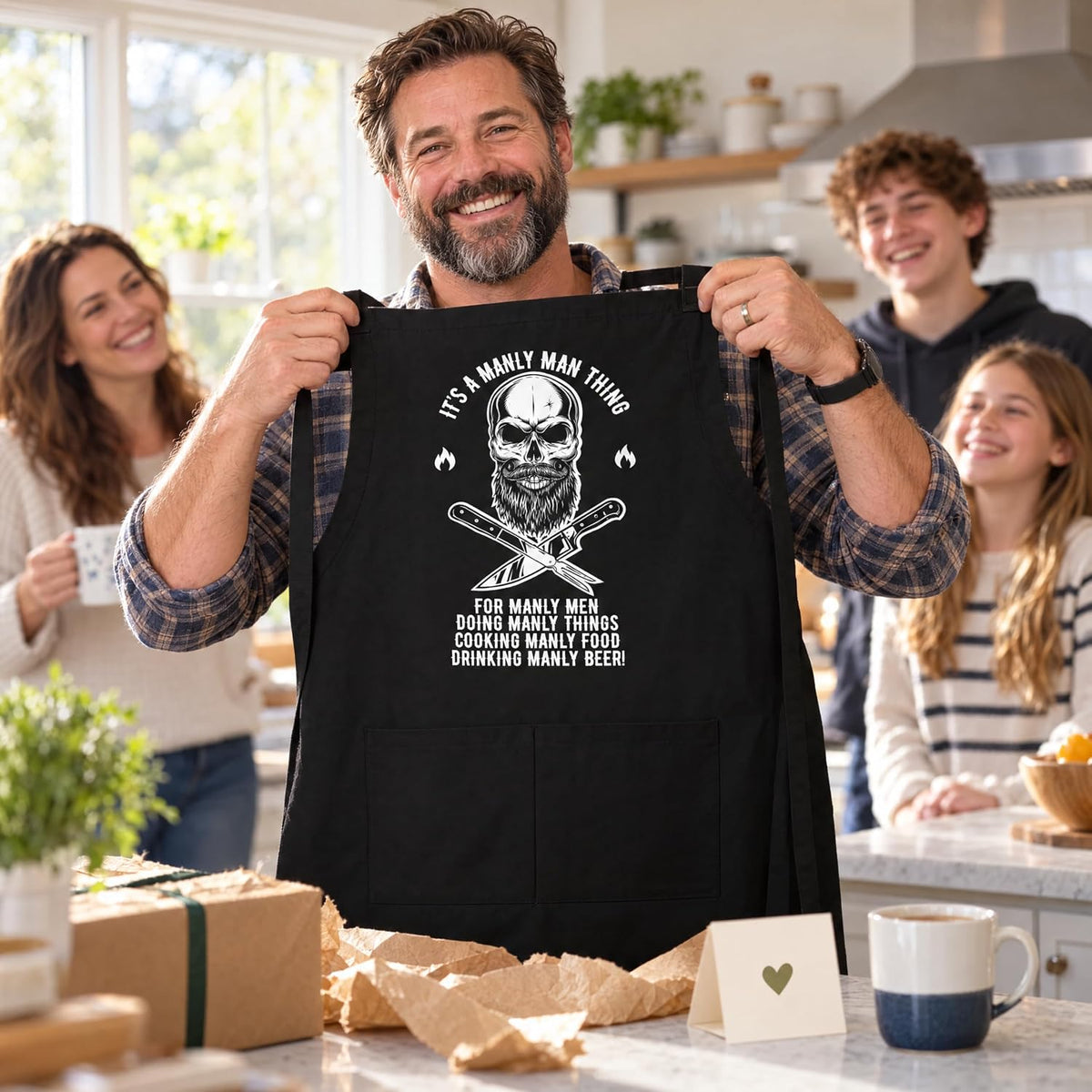 Man holding up his new skull BBQ apron gift with family in the kitchen