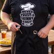Close-up of the Never Trust a Skinny Chef apron with a thermometer and bottle opener in the pocket