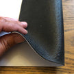 Hand lifting the corner of the bar runner to show the non-slip rubber backing